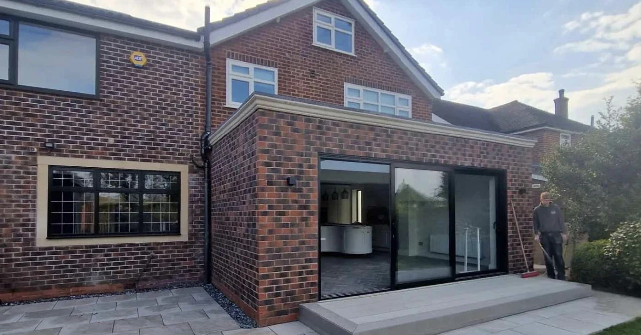 Single-storey brick extension with dark-framed sliding doors